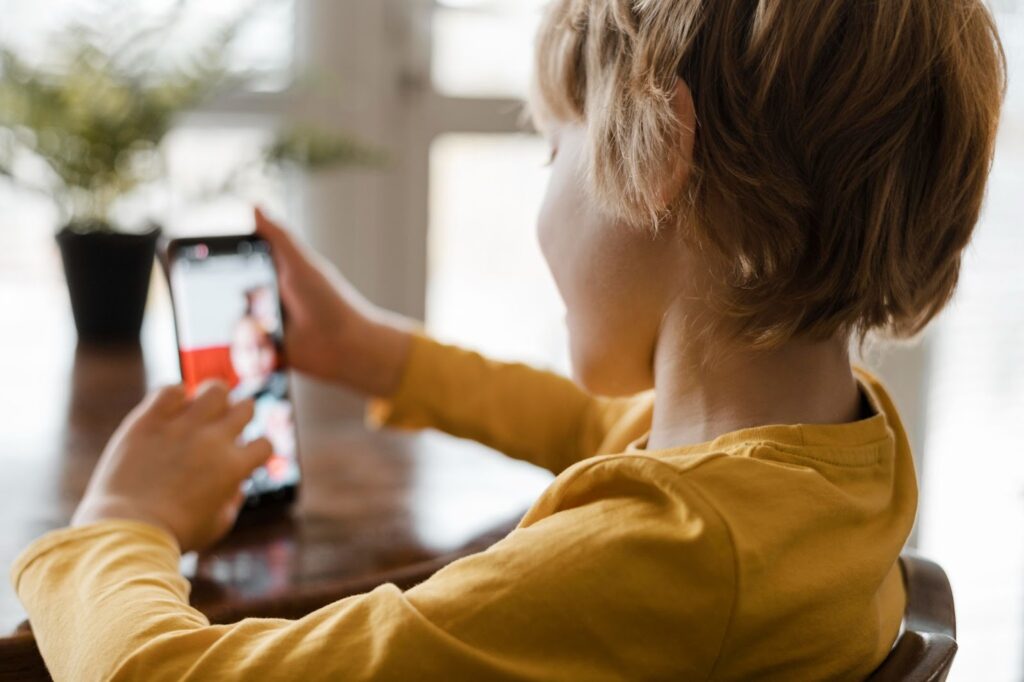 A young boy looking at his phone while recording a video for Instagram.