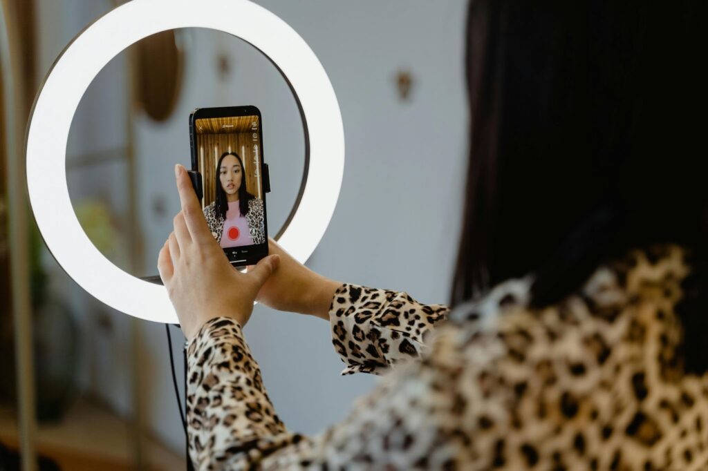 A young woman recording a video for her Instagram Stories, holding her smartphone.