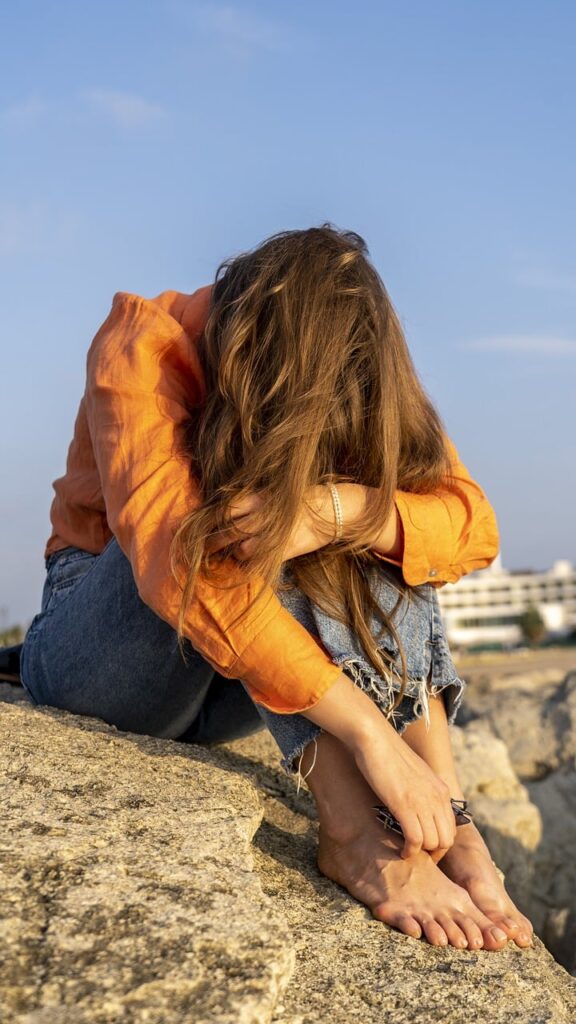 A woman sitting down, looking upset while holding her phone